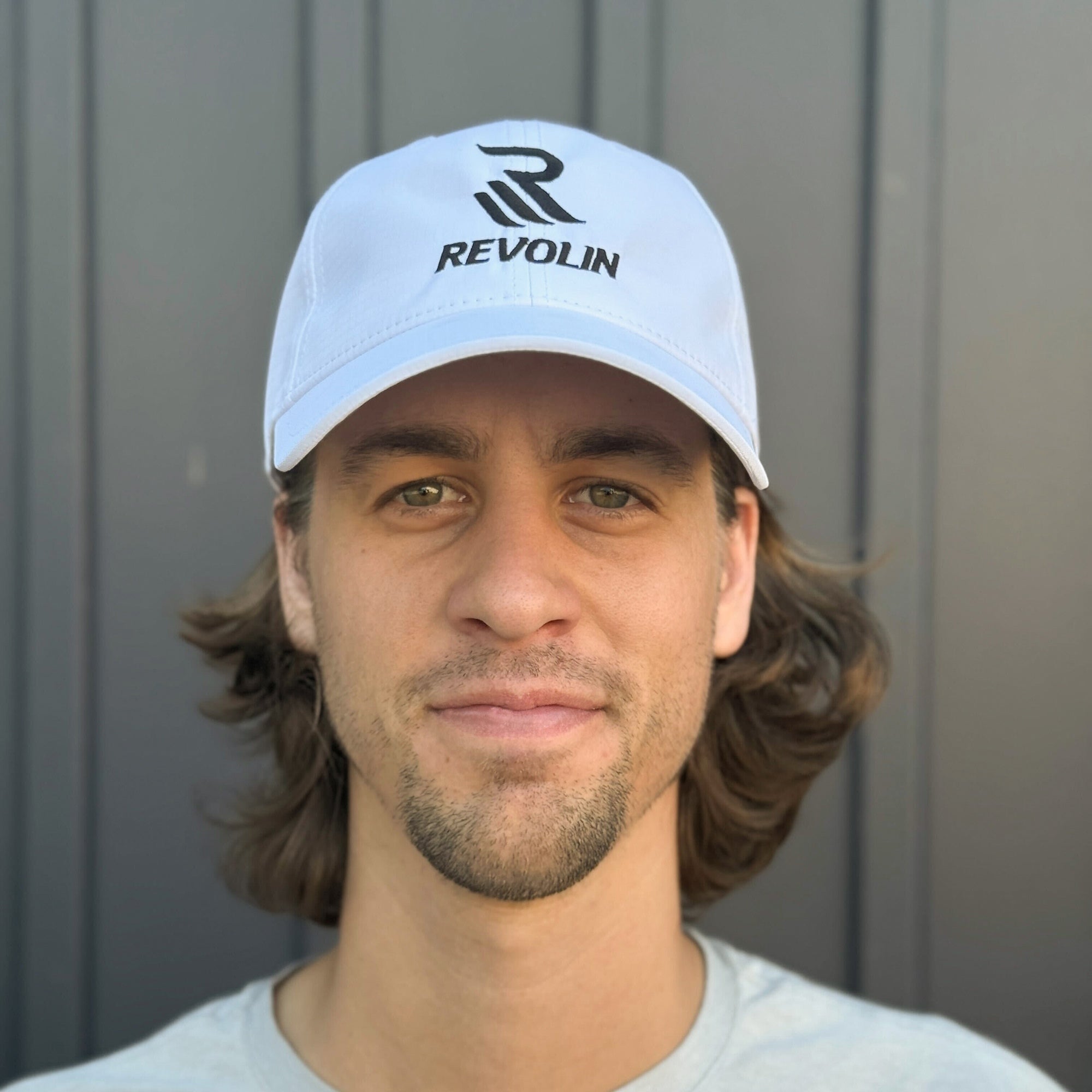Person wearing a white cap with 'REVOLIN' logo against a gray background