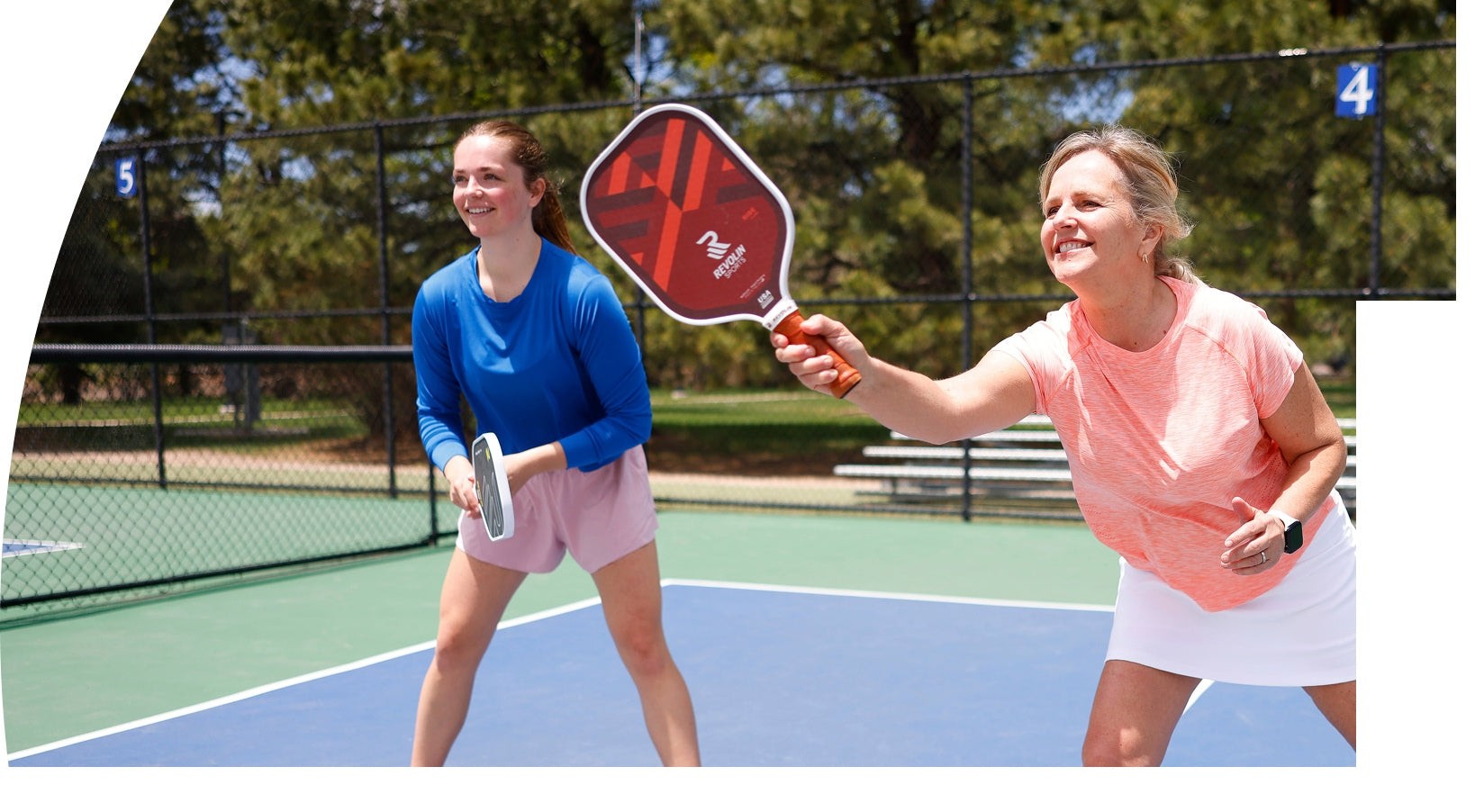 Two women playing pickleball on an outdoor court