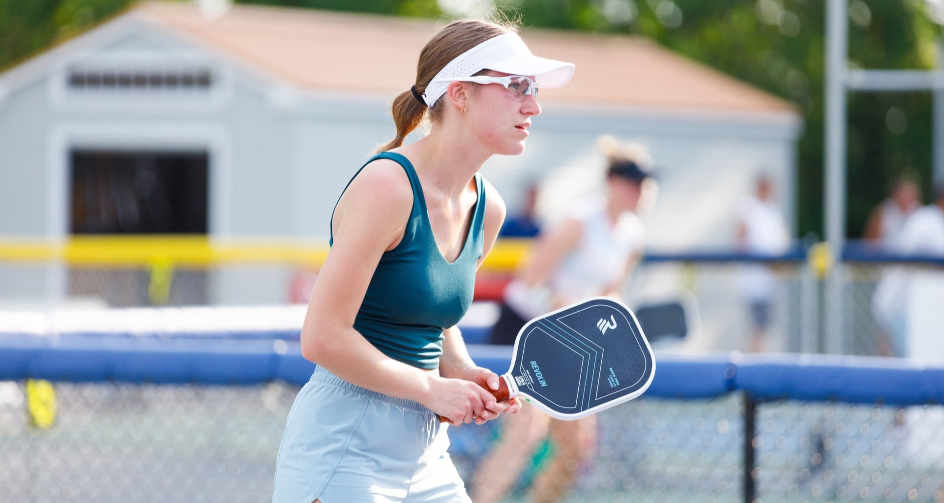 Woman playing pickleball on a court with a blurred background