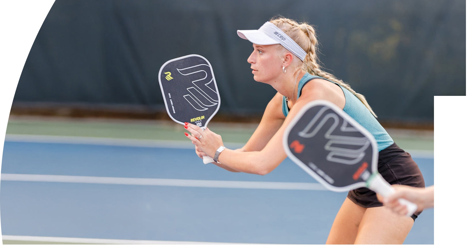 Woman playing pickleball on a court with a Revolin Drift paddle. 